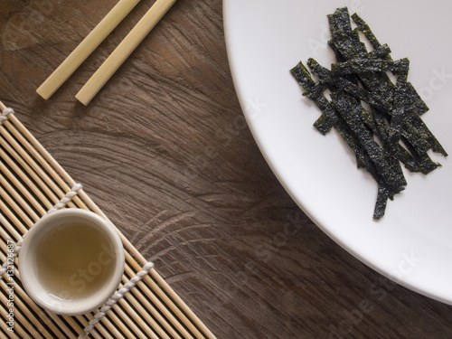 Dry Seaweed on White Dish and tea and Chopsticks on Wood Table photo