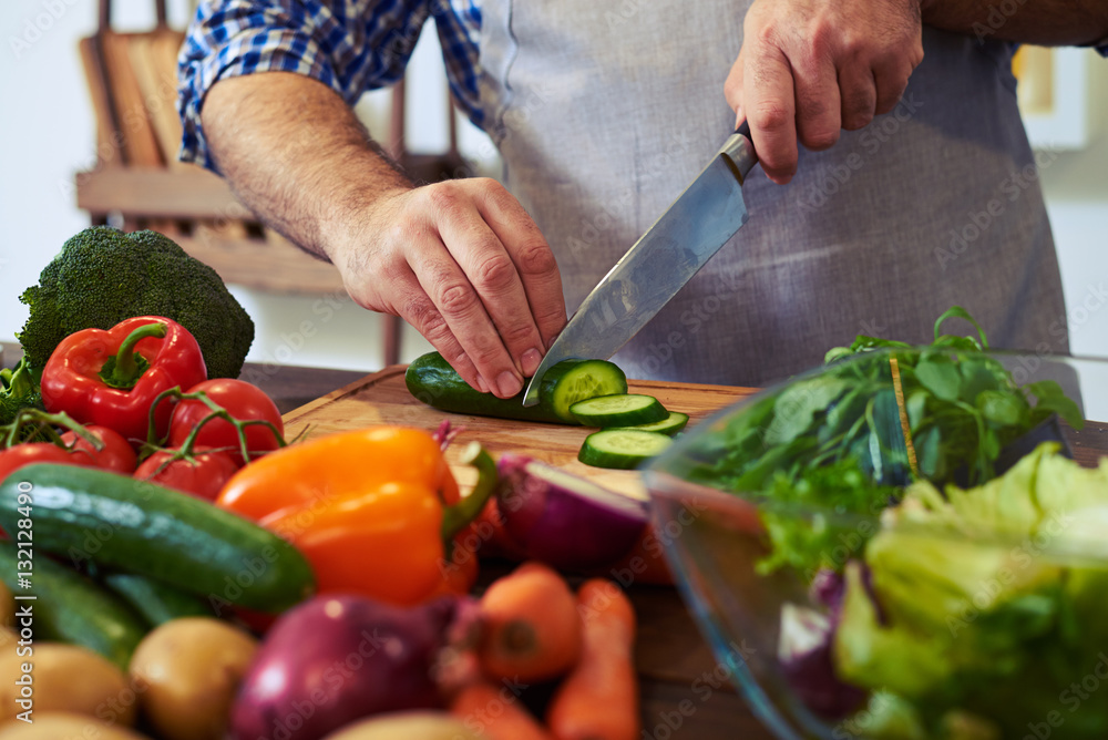Chef slicing cucumber with a knife on chopping board Chef slicing cucumber with a knife on chopping board
