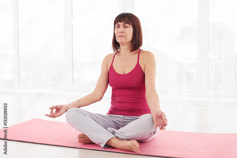 Fototapeta premium Concentrated female in sportswear meditating in lotus position w