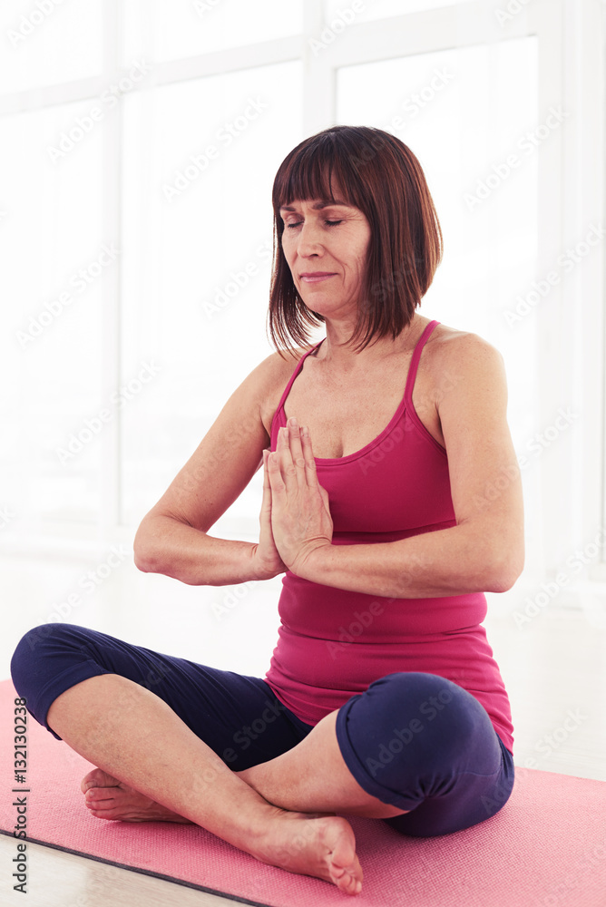 Mid shot of woman sitting on the mat and meditating