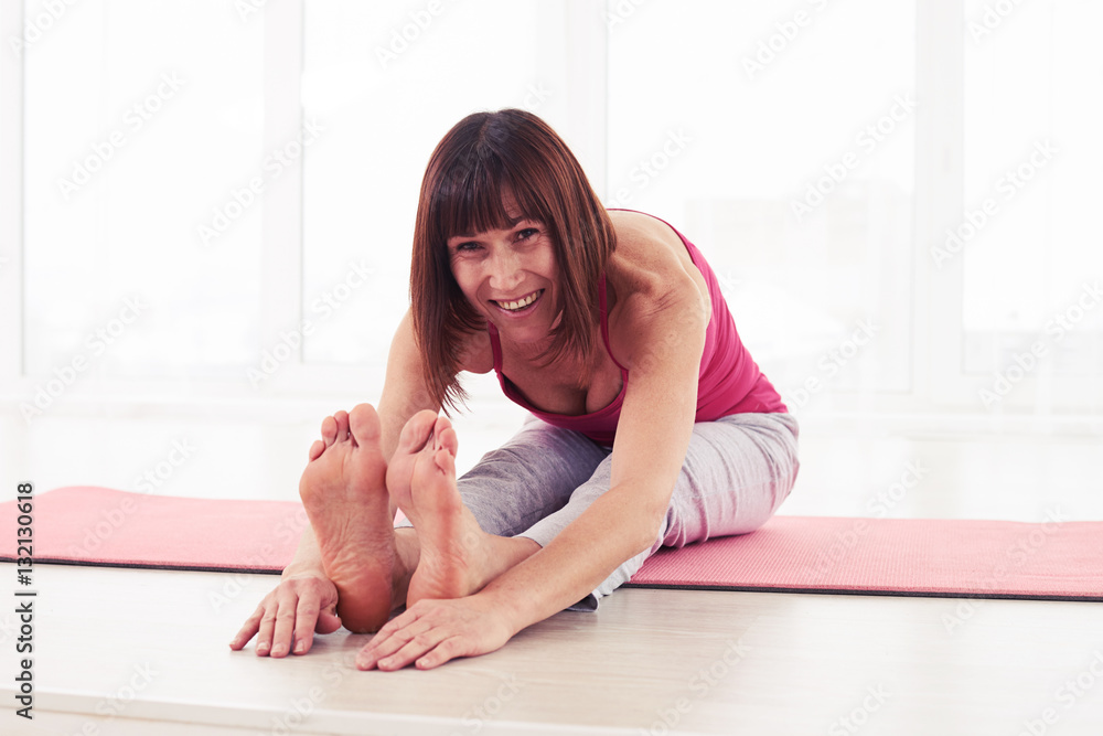 Positive smiling female in seated forward bend yoga pose holding
