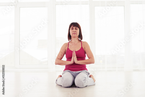 Fototapeta Naklejka Na Ścianę i Meble -  Slim woman meditating in the gym sitting on the yoga mat