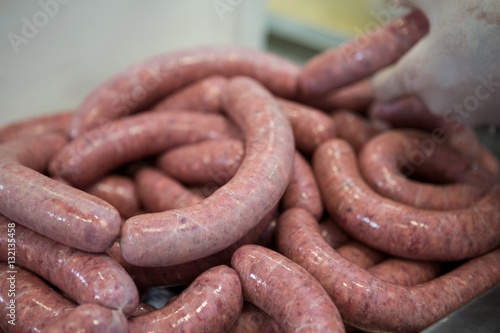 Butcher processing sausages in meat factory photo