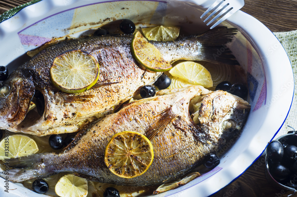 Baked in oven sea fish dorado with lime, olives and onion.
Grilled dorada fish on plate, close-up.