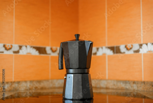 Close-up of black coffee pot on top of a ceramic hob photo