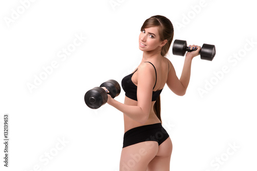 Girl with a beautiful figure shows the ass in bikini. She is holding the dumbbells back to the viewer