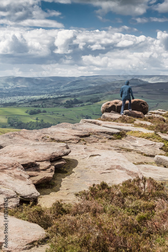 Woman stands on top of Stanage Edge rocks in Derbyshire enjoying photo