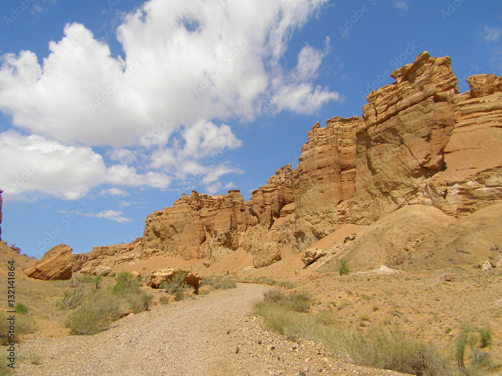 Road in desert canyon with blue sky and clouds