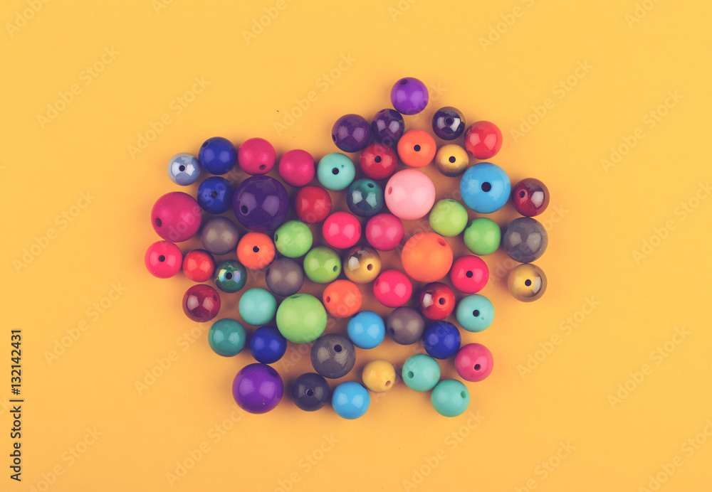 many colored glass pearls beads on yellow background many colored glass pearls beads on yellow background