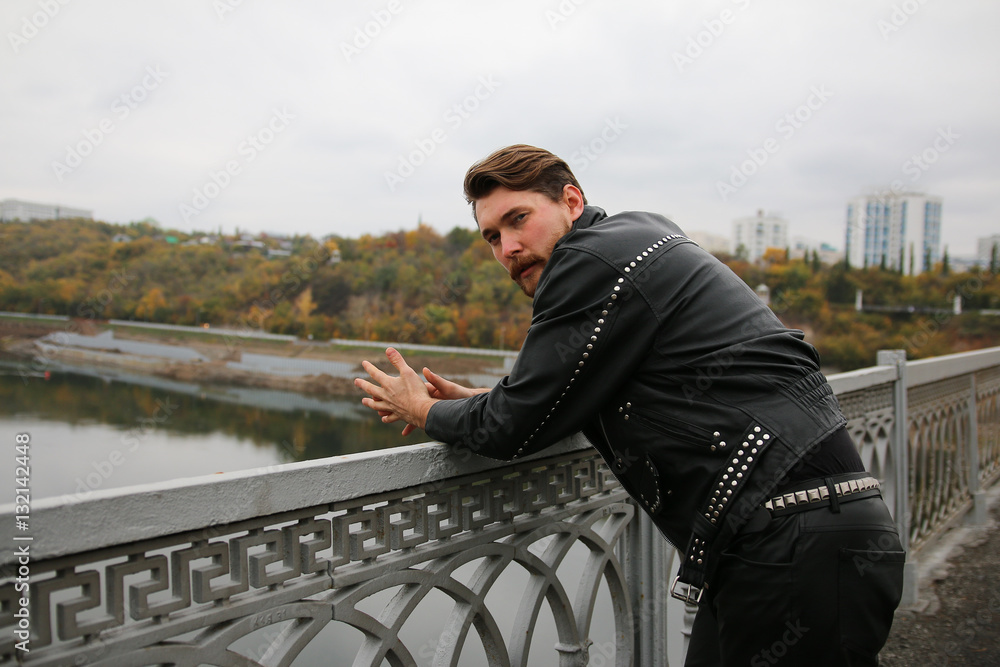 Man in black leather jackets looking at river