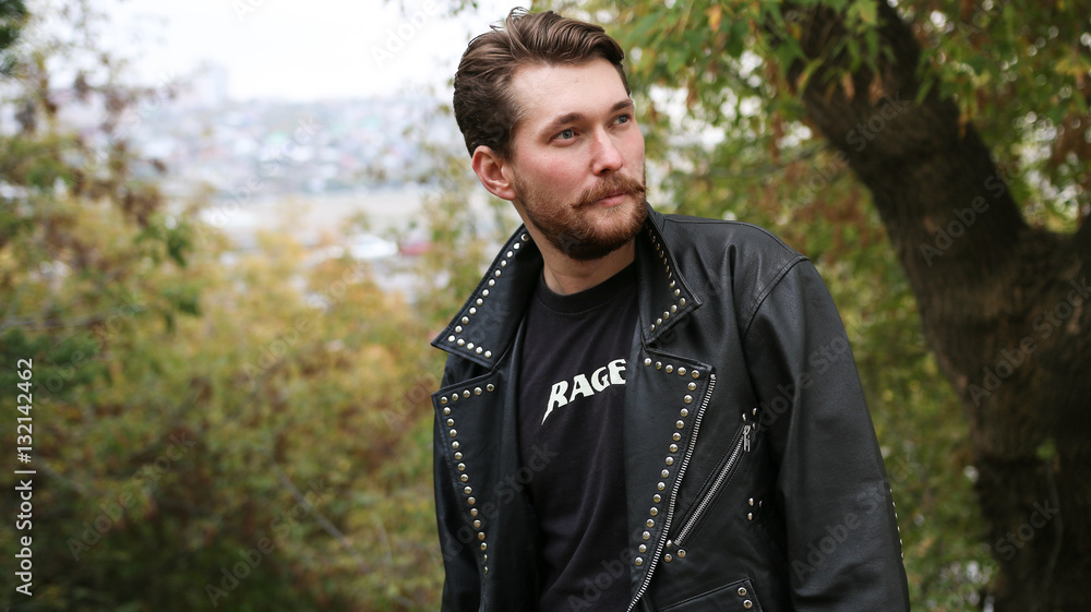 Bearded man in black leather jackets in a forest