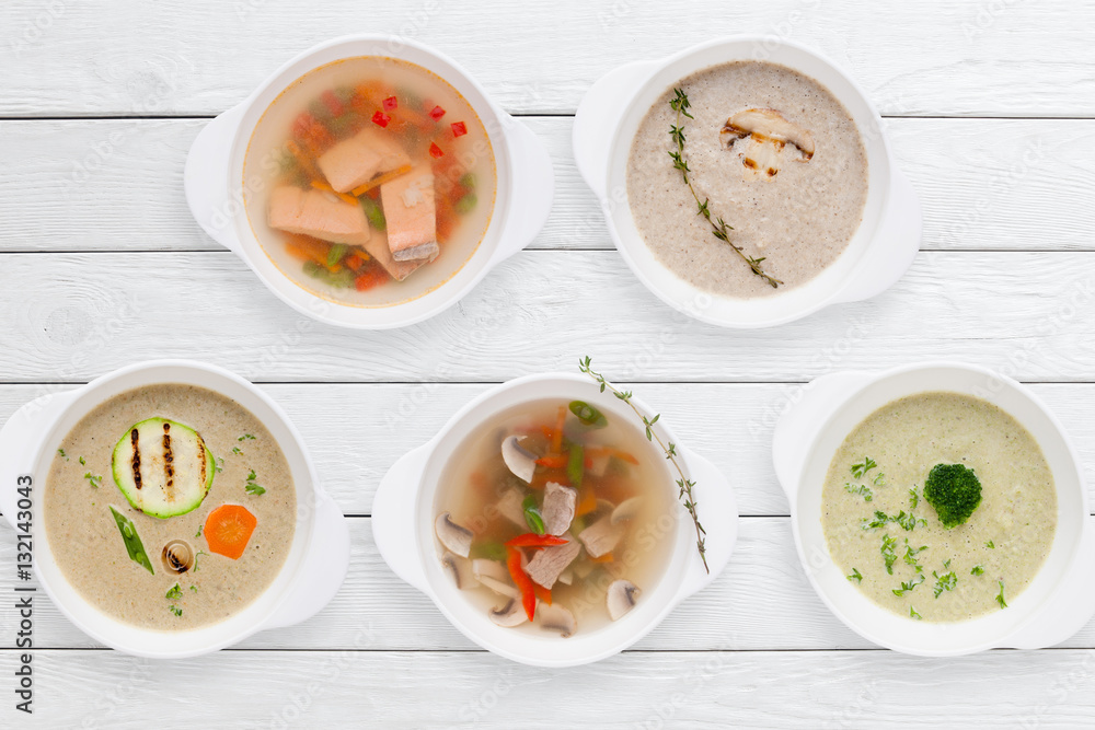 Variation of tasty restaurant hot dishes flat lay. Top view on white wooden table with set of different soups. Worldwide cuisine, healthy food, buffet, lunch, menu concept Variation of tasty restaurant hot dishes flat lay. Top view on white wooden table with set of different soups. Worldwide cuisine, healthy food, buffet, lunch, menu concept