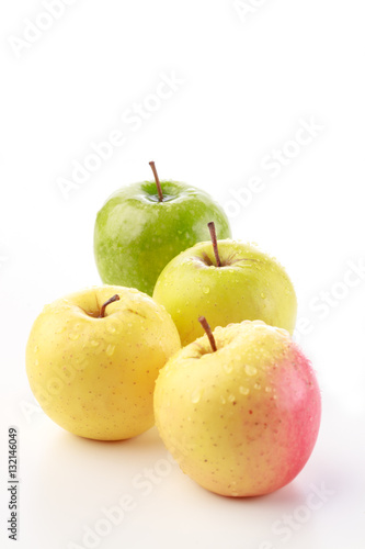 Bunch of yellow, pink and green apples against a white background