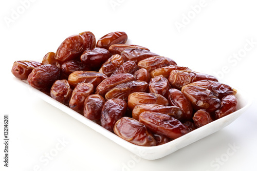 Fresh dates on a white plate against a white background