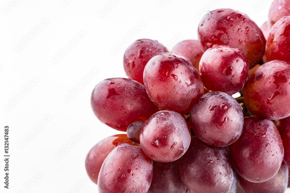 Close up of shiny bundle of purple grapes with water droplets on a white background Close up of shiny bundle of purple grapes with water droplets on a white background