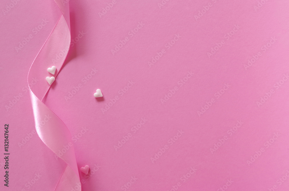 Schleifenband mit Zuckerherzen auf rosa Untergrund