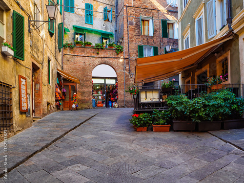 Fototapeta Naklejka Na Ścianę i Meble -  Medieval narrow street in Siena, Tuscany, Italy. Siena is capital of province of Siena. Historic centre of Siena has been declared by UNESCO a World Heritage Site