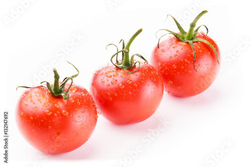 Three fresh red tomatoes in perspective in a diagonal line on a white background