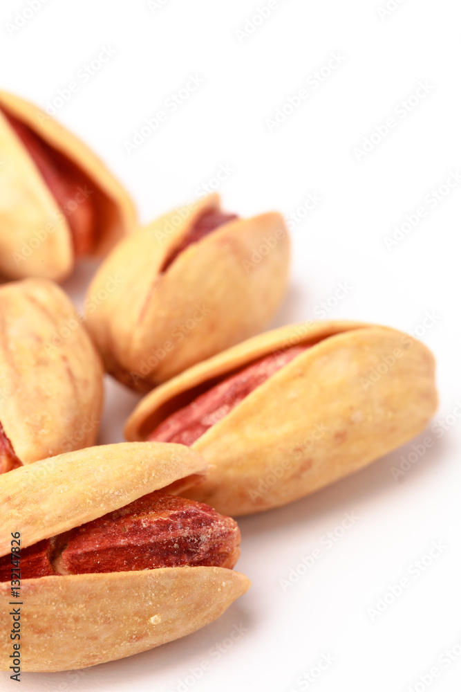 Closeup of salted pistachios with shells spread out on a white background Closeup of salted pistachios with shells spread out on a white background