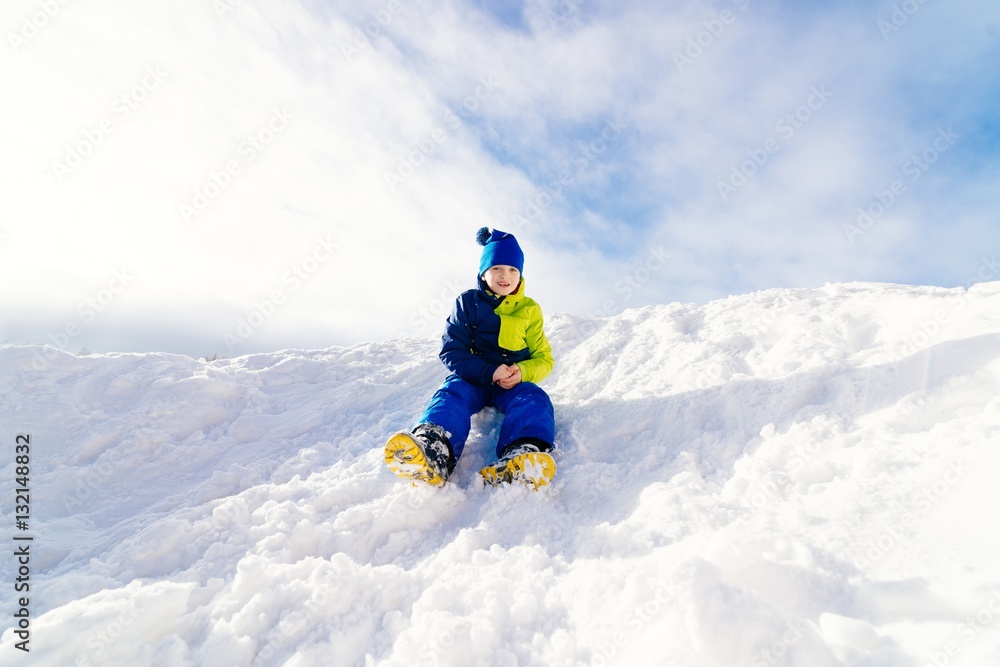 Happy child sliding from little snowy hill