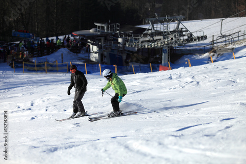 Kobieta i mężczyzna zjeżdżają na nartach z góry po śniegu.