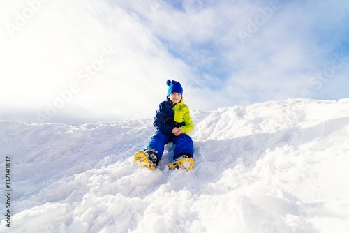 Happy child sliding from little snowy hill