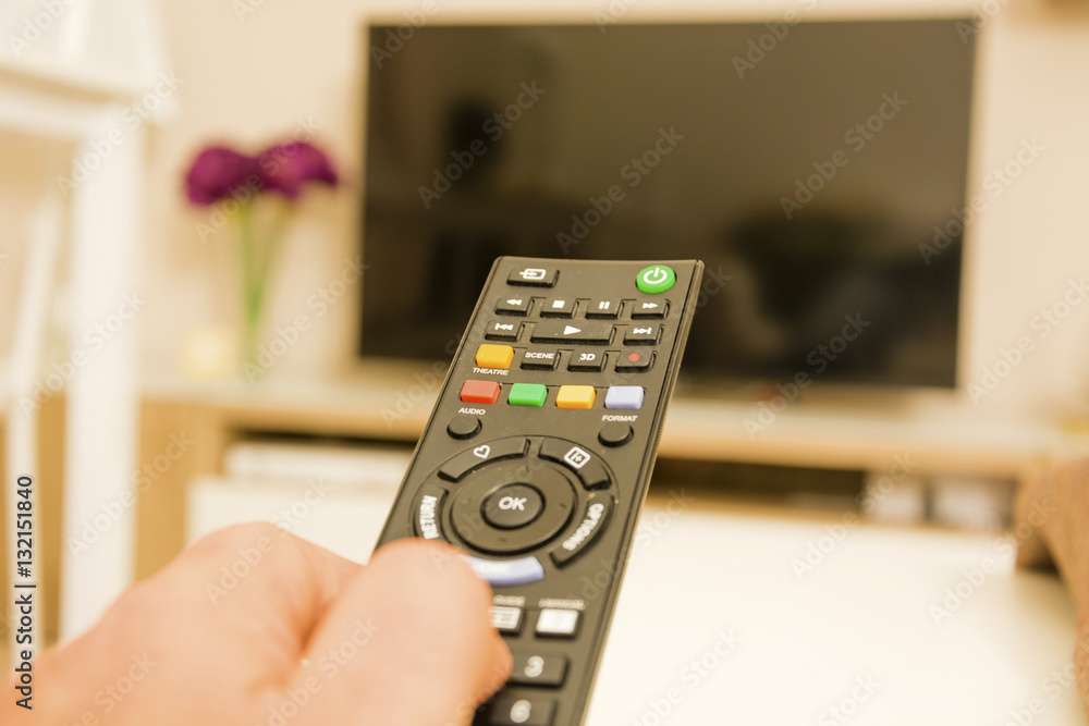 tv remote control with a thumb on buttons tv remote control with a thumb on buttons