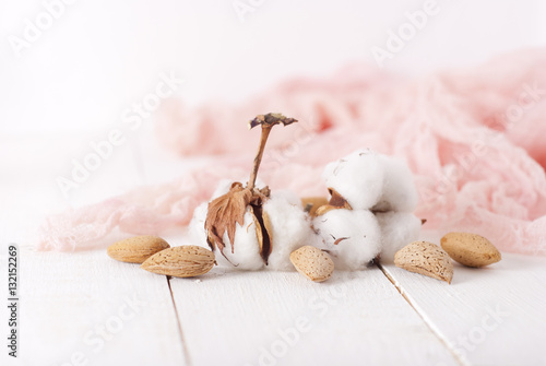 almonds and cotton with rose textile on whte wooden table. selec photo