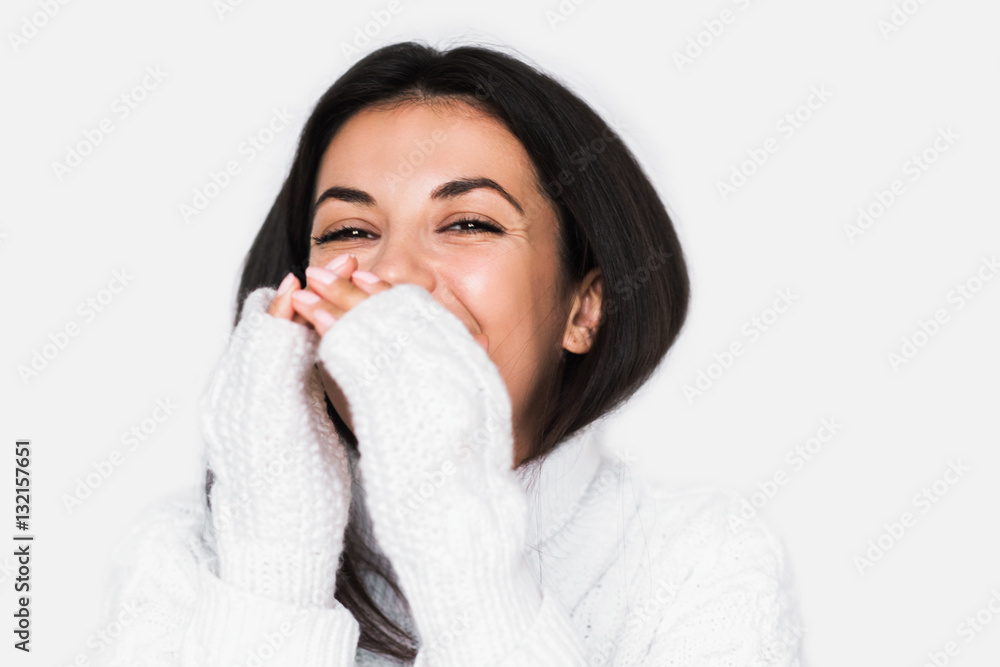 Beautiful young happy woman laughing sincerely in white sweater on light grey background. Pretty brunette smile woman studio portrait. Positive mood. Beautiful young happy woman laughing sincerely in white sweater on light grey background. Pretty brunette smile woman studio portrait. Positive mood.