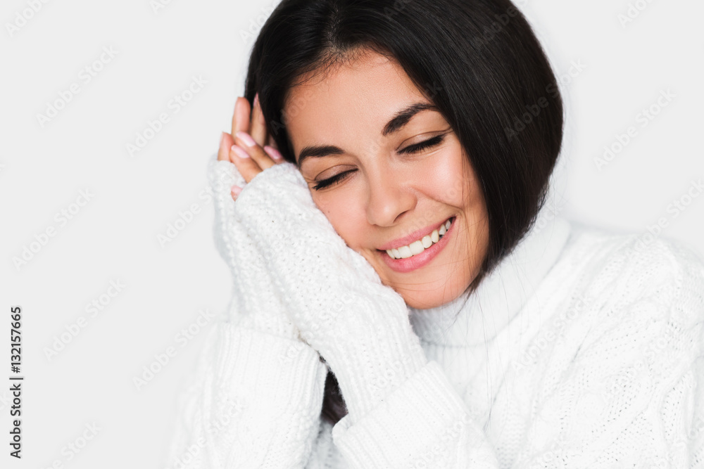 Portrait of beautiful young happy dreamy womanwith closed eyes in white sweater on light grey background. Pretty brunette model with beautiful healthy smile, studio portrait. Healthy mood. Portrait of beautiful young happy dreamy womanwith closed eyes in white sweater on light grey background. Pretty brunette model with beautiful healthy smile, studio portrait. Healthy mood.