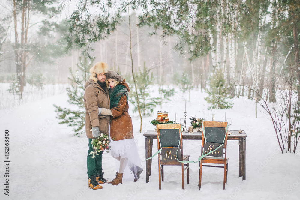 The bride and groom exchange their wedding next to the table. Wedding ceremony in winter.