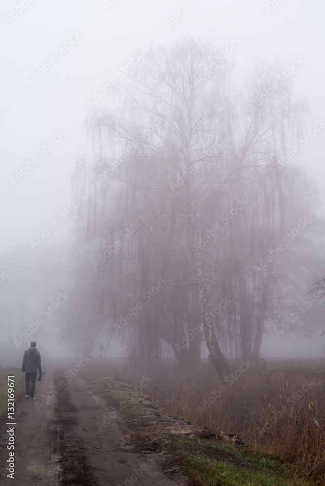 samotny mężczyzna spacerujący w gęstej mgle - obrazy, fototapety, plakaty 