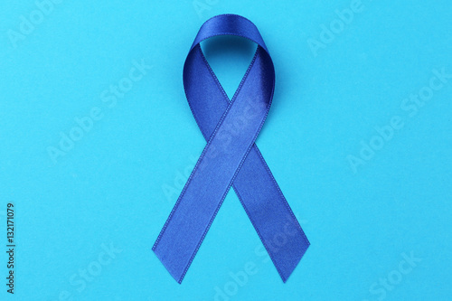 Blue ribbon on color background. Colon cancer concept