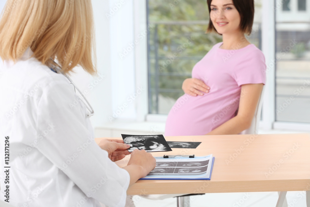 Doctor showing ultrasound photo to pregnant woman Doctor showing ultrasound photo to pregnant woman