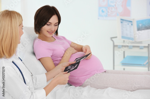 Gynecologist showing ultrasound photo to pregnant woman