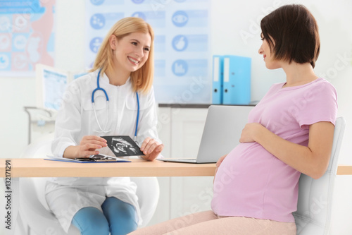 Doctor showing ultrasound photo to pregnant woman