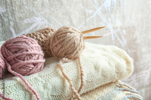 Knitting yarn and needles on pile of plaids, closeup