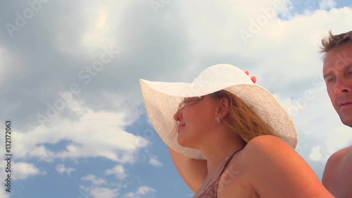 Happy loving middle-aged couple at the beach. Happy couple enjoying romantic vacation, man hugging his wife, kissing and smiling over blue sky. Slow motion 240 fps. Full HD 1080p