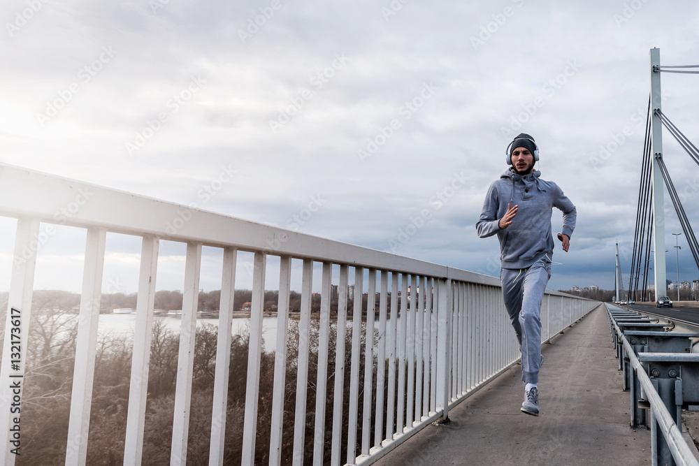 Man runner with earphones having intensive training outdoors
