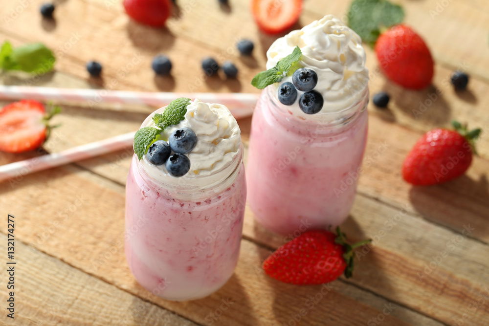 Tasty milk shake cocktails with berries on wooden table Tasty milk shake cocktails with berries on wooden table