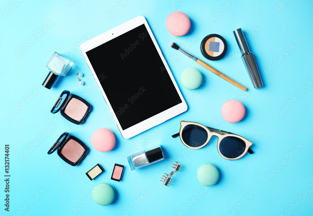 Makeup cosmetic with macaroons and tablet on blue background