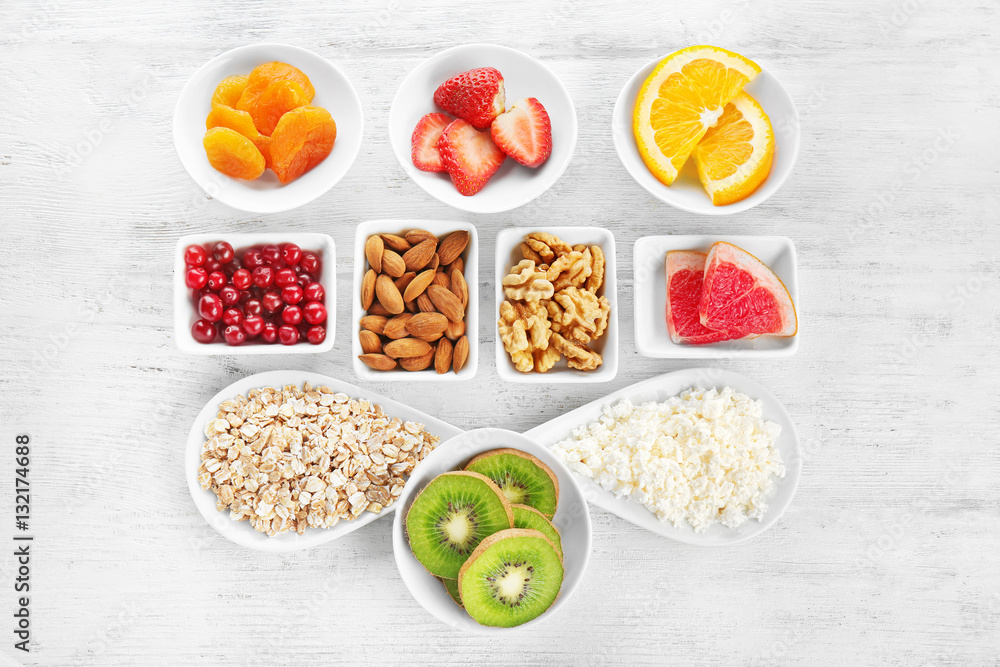 Set of diet products in saucers on wooden background Set of diet products in saucers on wooden background