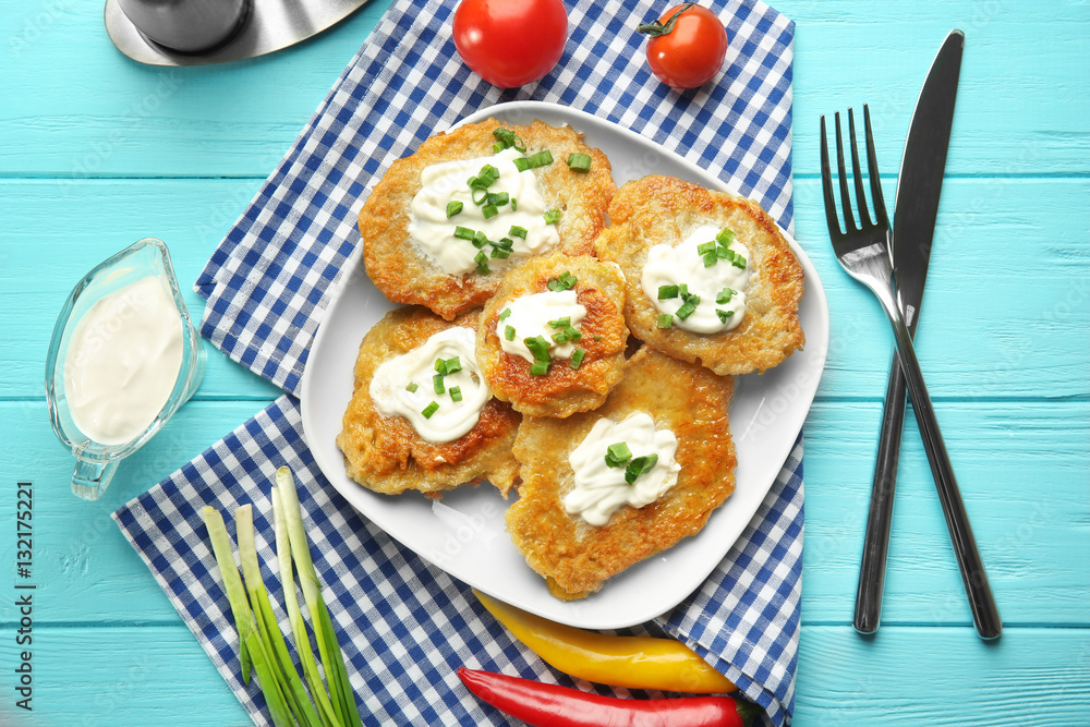 Plate with tasty potato pancakes for Hanukkah and some ingredients on wooden table Plate with tasty potato pancakes for Hanukkah and some ingredients on wooden table