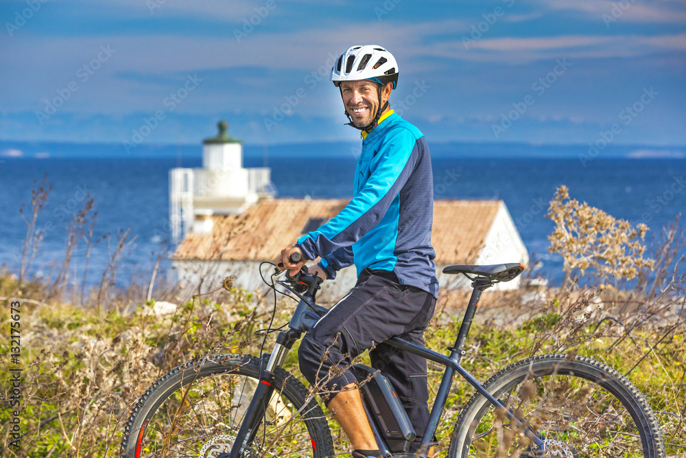 Fototapeta premium Mountainbiker mit Ebike am Meer