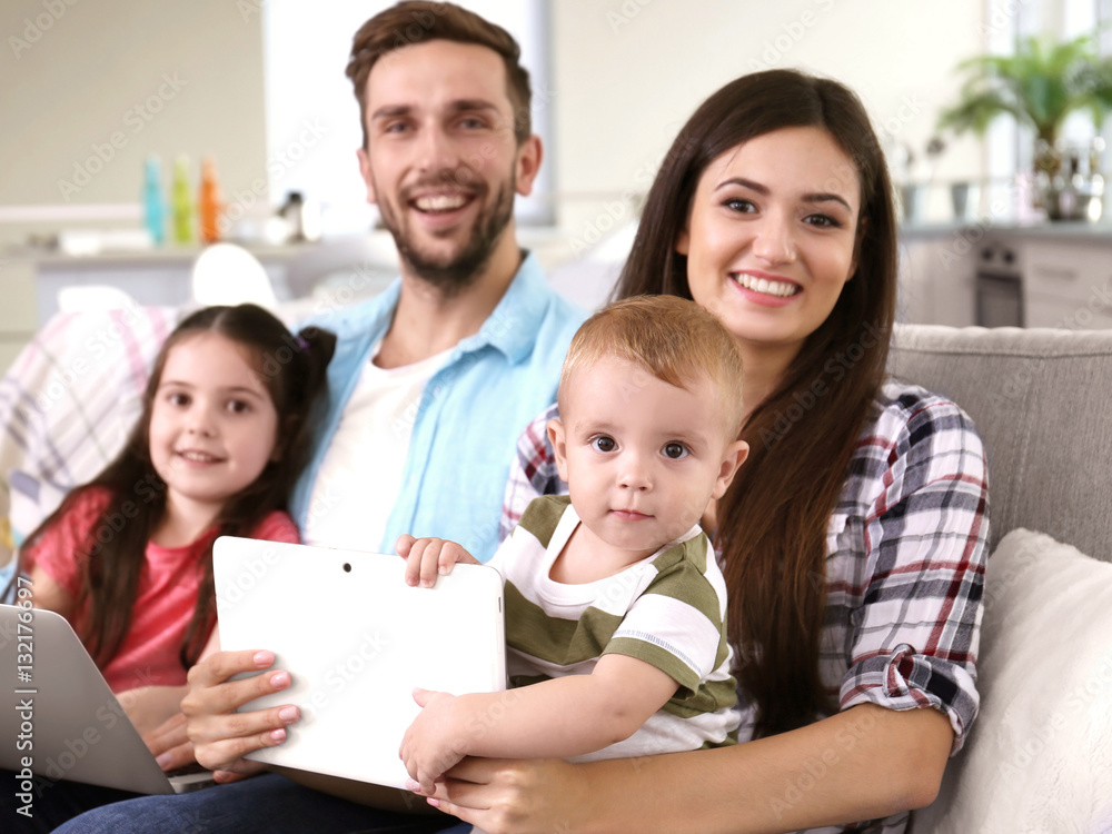 Happy family with gadgets on couch Happy family with gadgets on couch