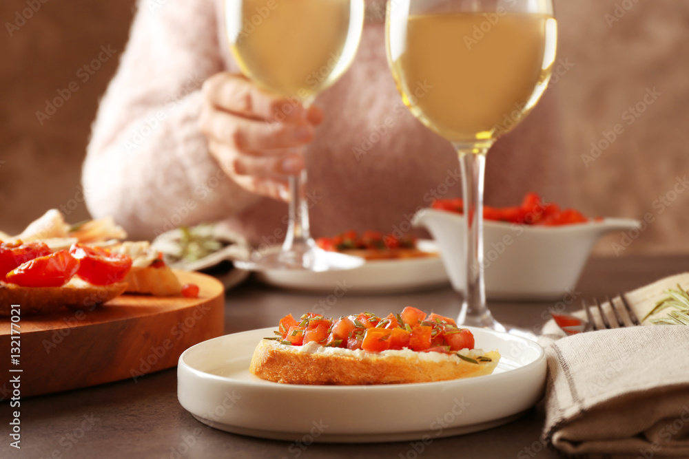 Woman sitting at table with glass of wine and tasty bruschetta Woman sitting at table with glass of wine and tasty bruschetta