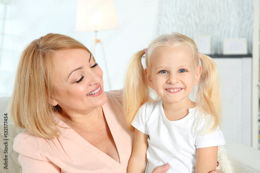 Cute happy girl with grandmother sitting on sofa at home Cute happy girl with grandmother sitting on sofa at home
