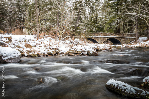 Winter river scene in the snowy forest and double arch stone bridge in background