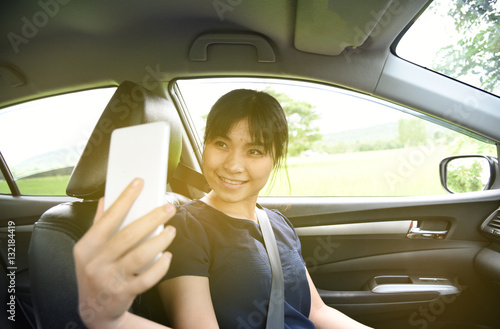 Woman taking a photo with smart phone in car with sunlight,Woman selfie in car