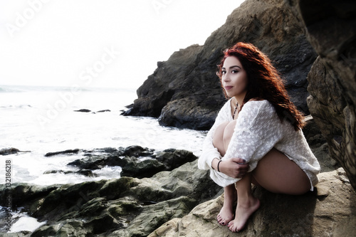 Latina Woman Sitting On Rocks At Ocean